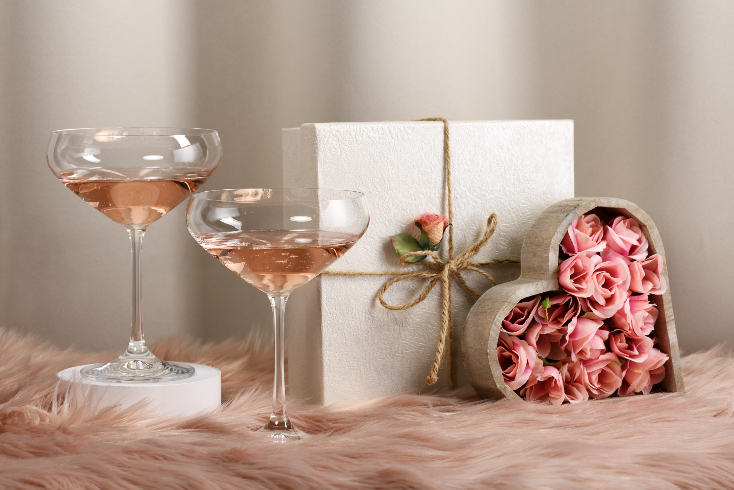 Two glasses with rose wine and decorated gifts